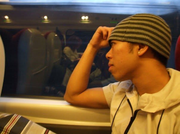 A younger Jenkin Lee sitting on a train and looking out of the window